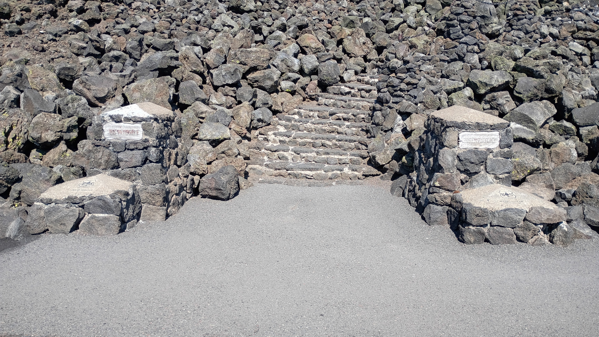 Stacked lava flow with stairs in between two nameplates. one reads Dee Wright. The other reads Observatory.