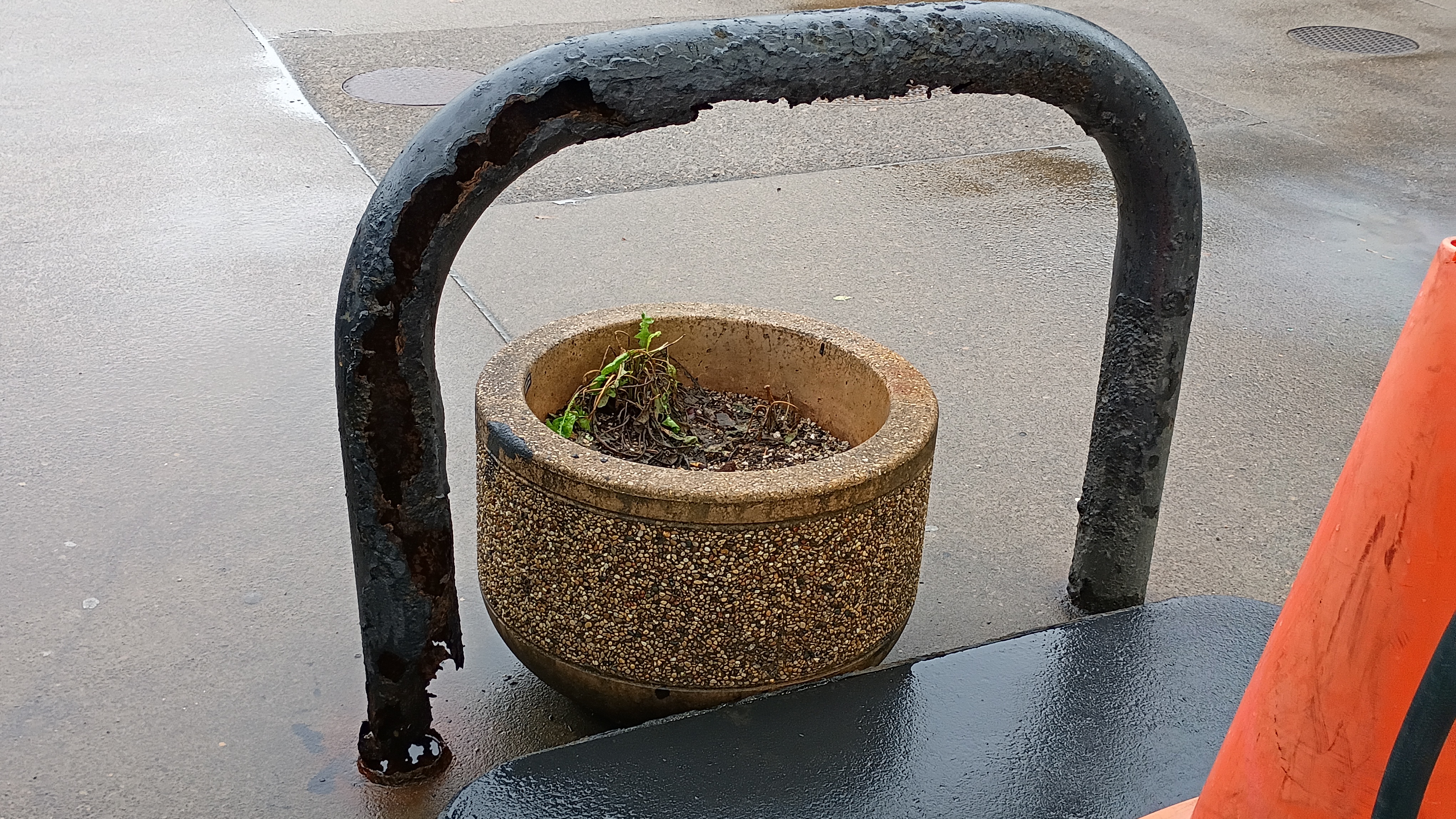 One of those big metal protectors that protect gas station pumps from vehicles. The barrier is completely rusted through, large chunks of it are missing and it seems that only the paint is holding the rest of it together. 	