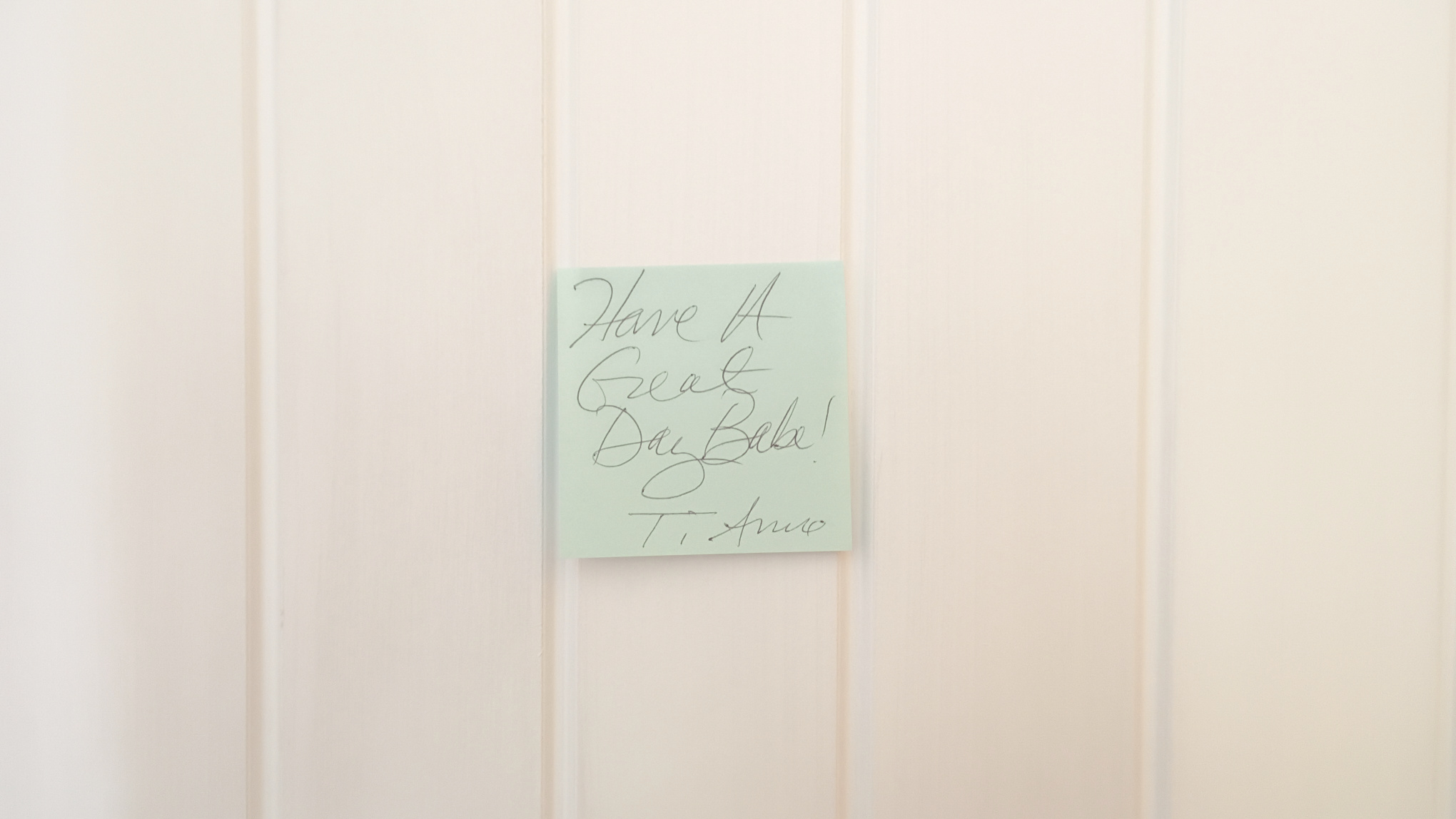 Sea green post-it note stuck to white door. Note reads, Have A Great Day Babe! Ti amo.