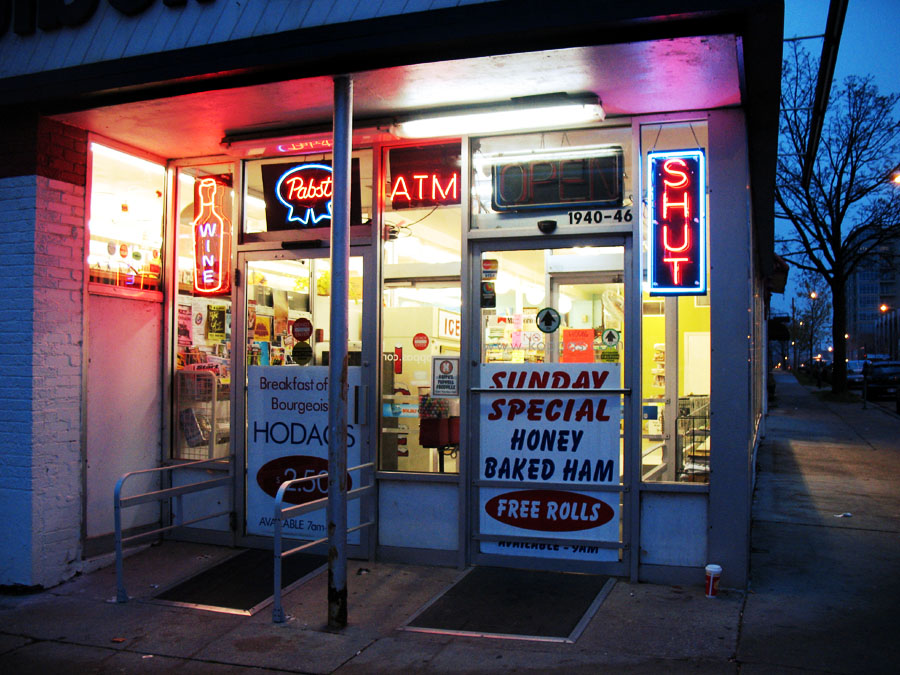 Not actually a Piggly Wiggly Front doors of a grocery store with signs showing weekly deals, an ATM, and a sign reading 'Shut'.
