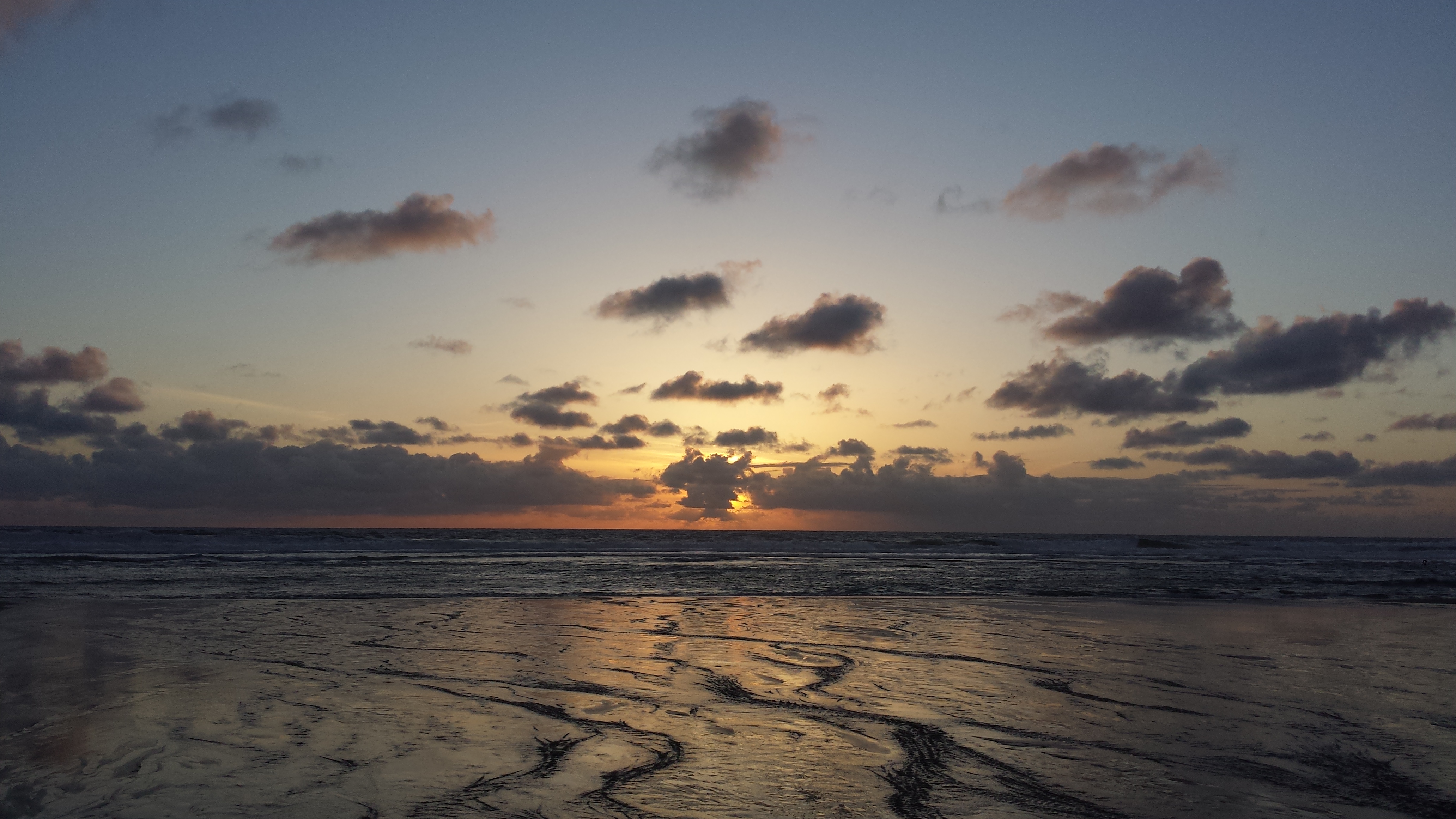 Sunset over the Pacific Ocean. Blue sky to orange. Low tide.