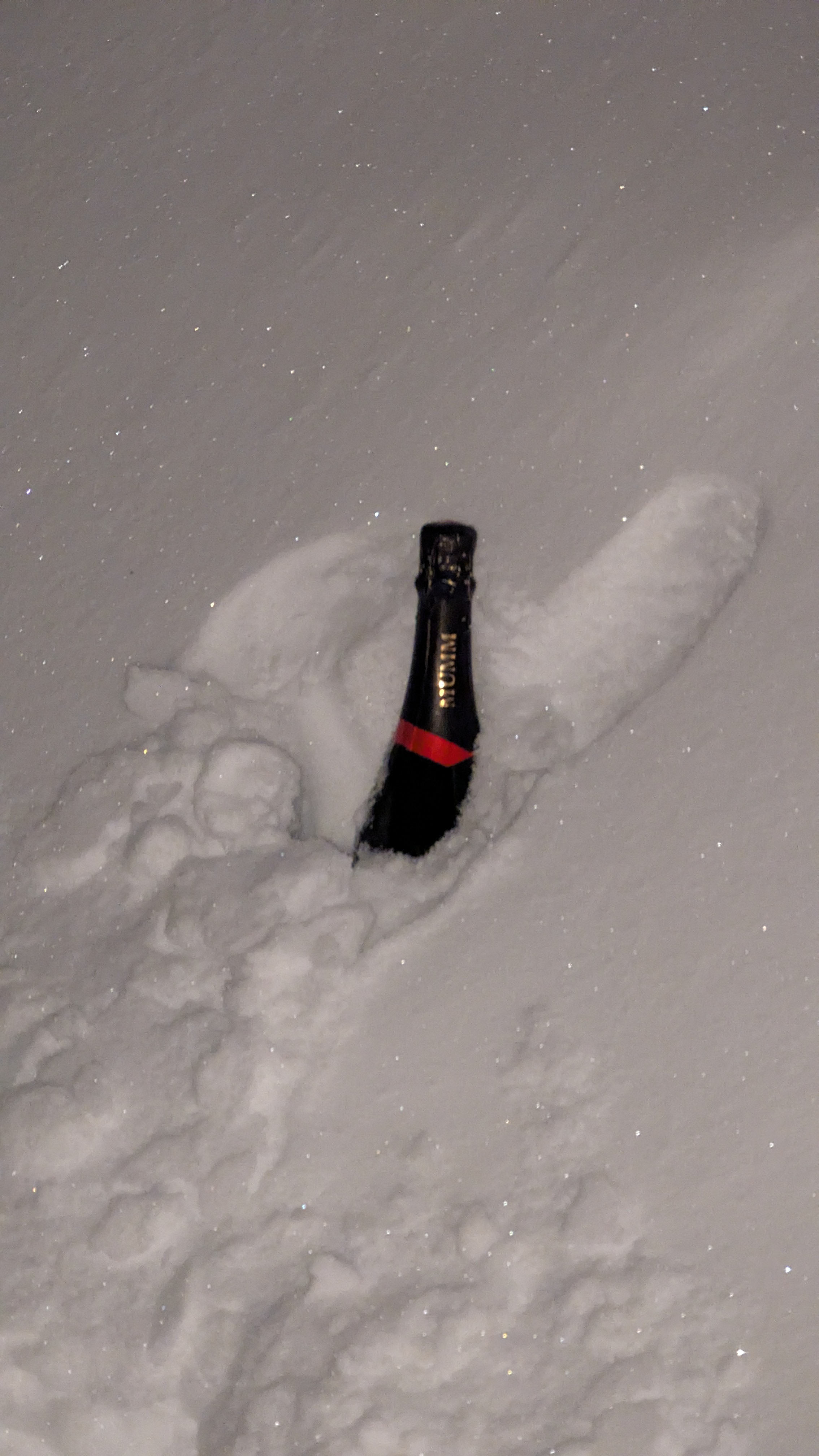 Nighttime. Snowbank. Champagne bottle hidden in snowbank.