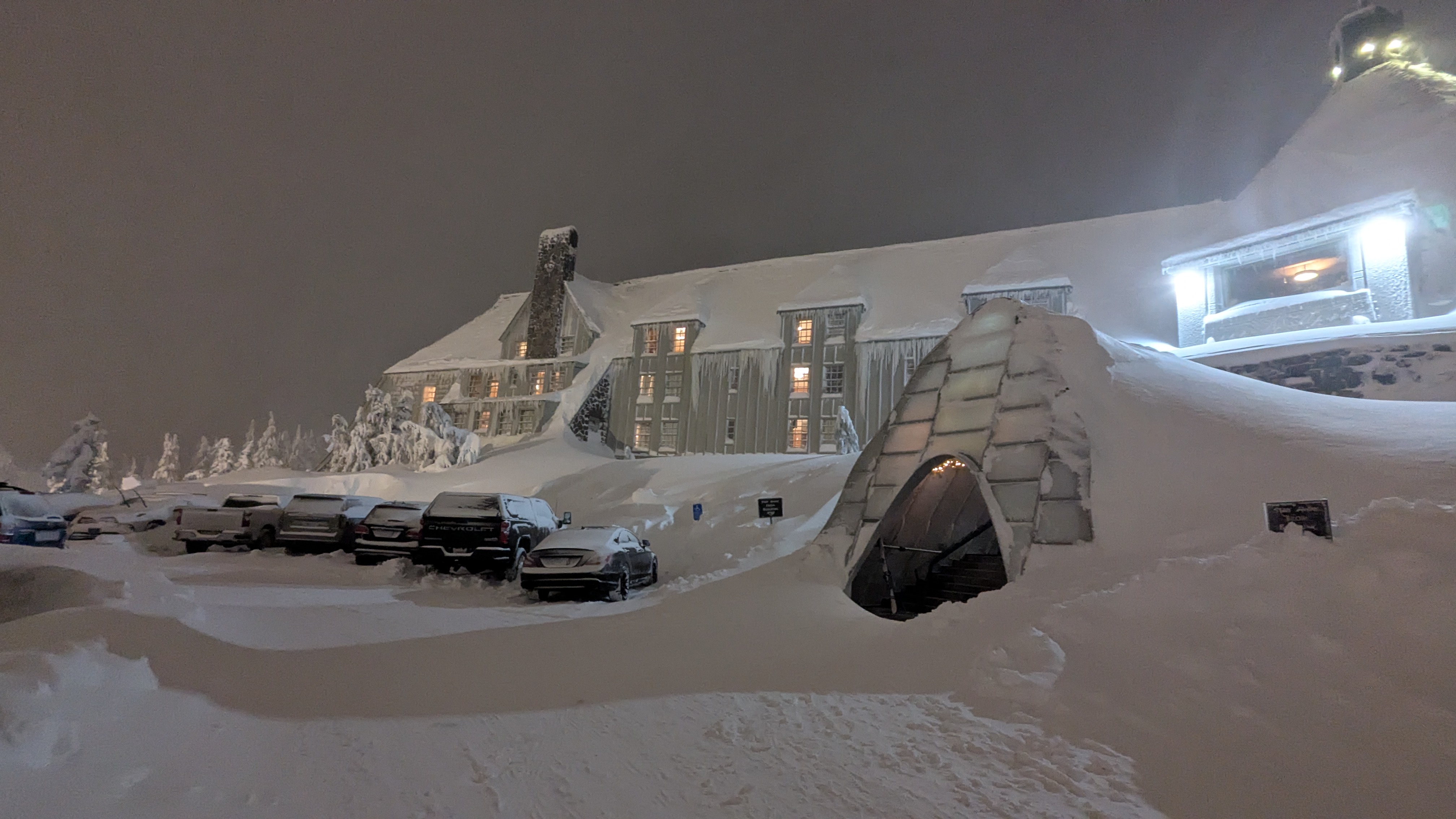 Winter alpine setting. Nighttime. Snow drifts dozens and dozens of feet high surrounding the main entrance to Timberline Lodge.