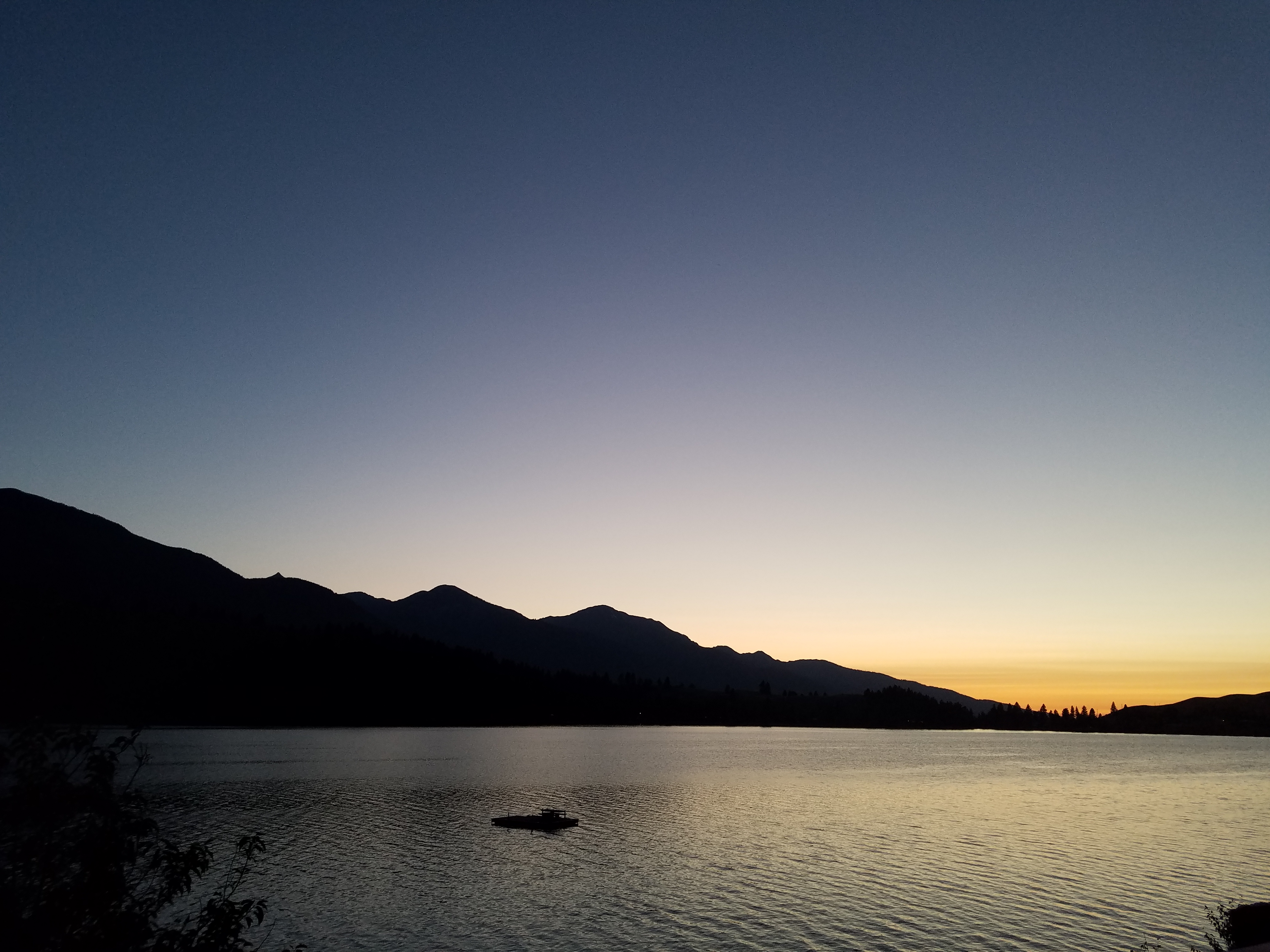 Night falling in the Wallowas. Just a bit of blue and yellow left in the sky. Mountains loom dark with Lake Wallowa in the foreground.