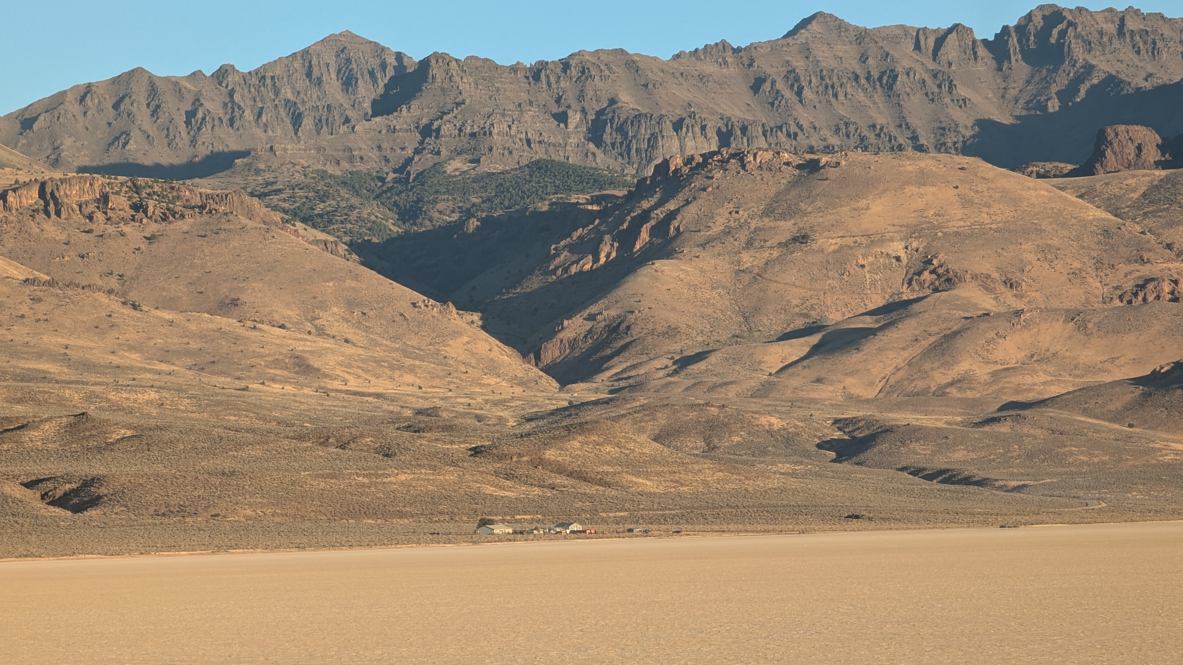 View from the playa with a zoomed in image of the Steens. You can make out a teeny tiny looking homestead between the playa and the mountains. floor.